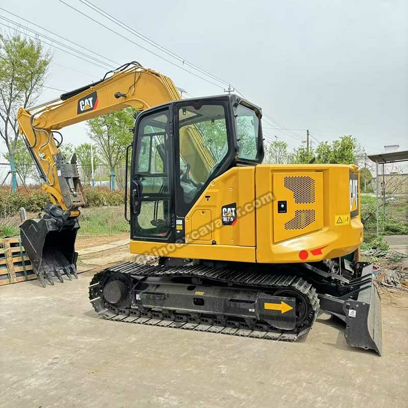 Front view of a Cat compact excavator with raised boom undergoing operational performance testing.