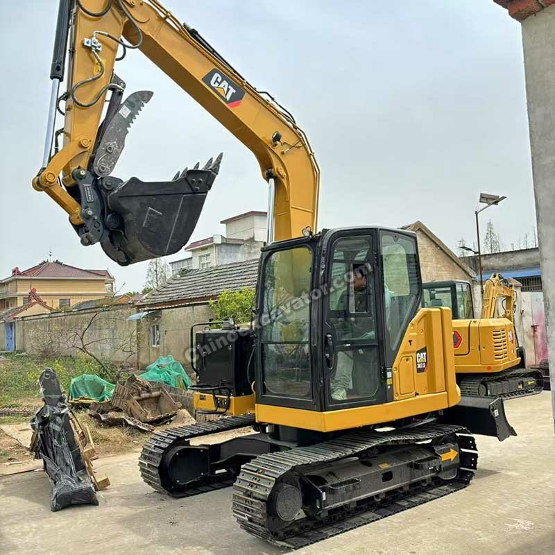 Side view of a Cat mini excavator with raised boom and hydraulic thumb attachment.